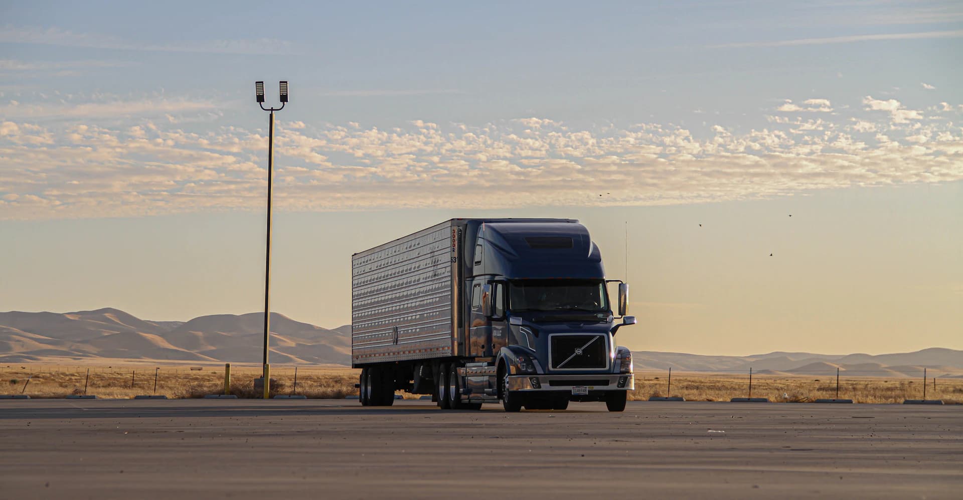 Long-haul semi truck parked at a highway rest stop at dawn